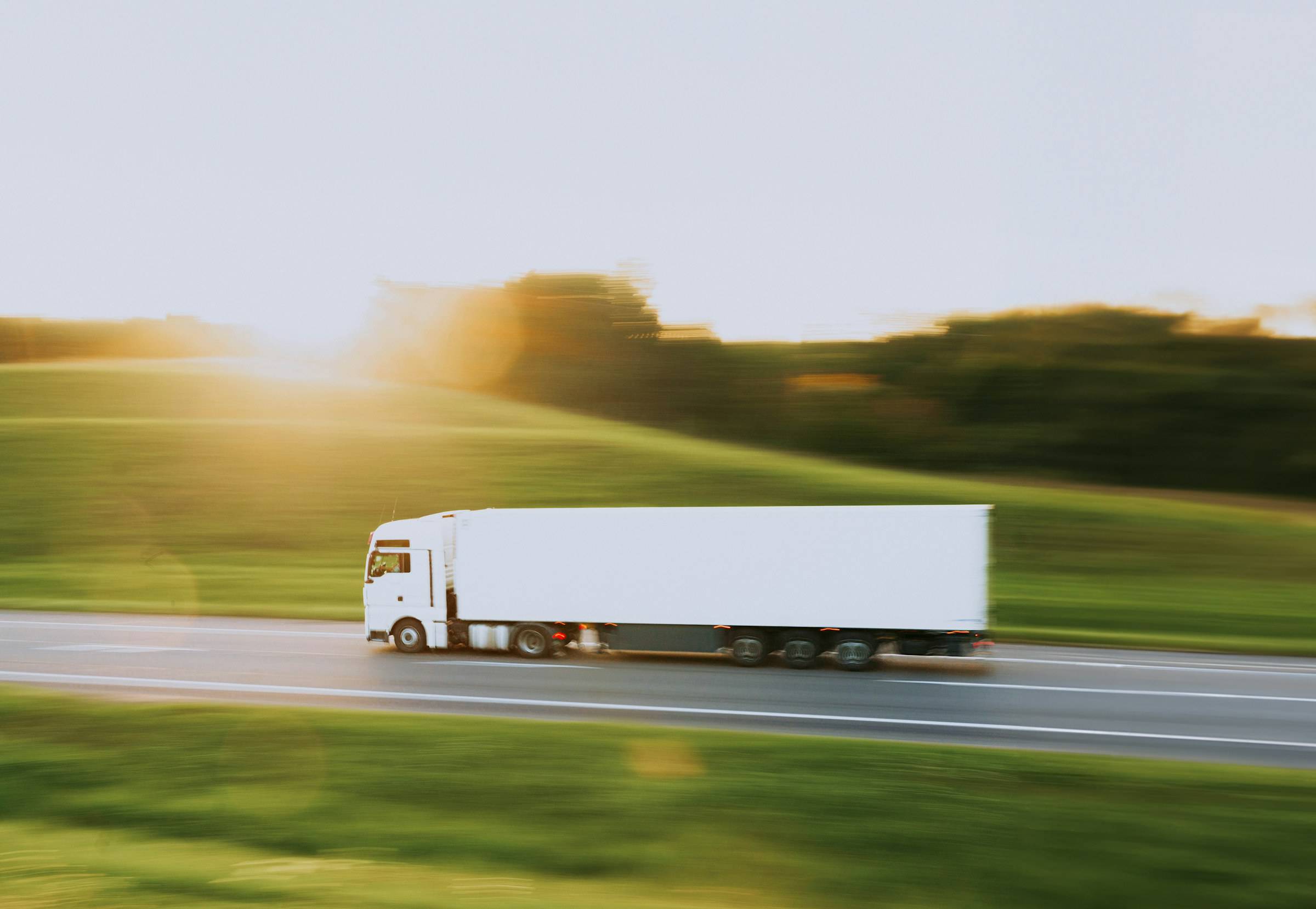 Camion cu semiremorcă albă pe autostradă, la apus