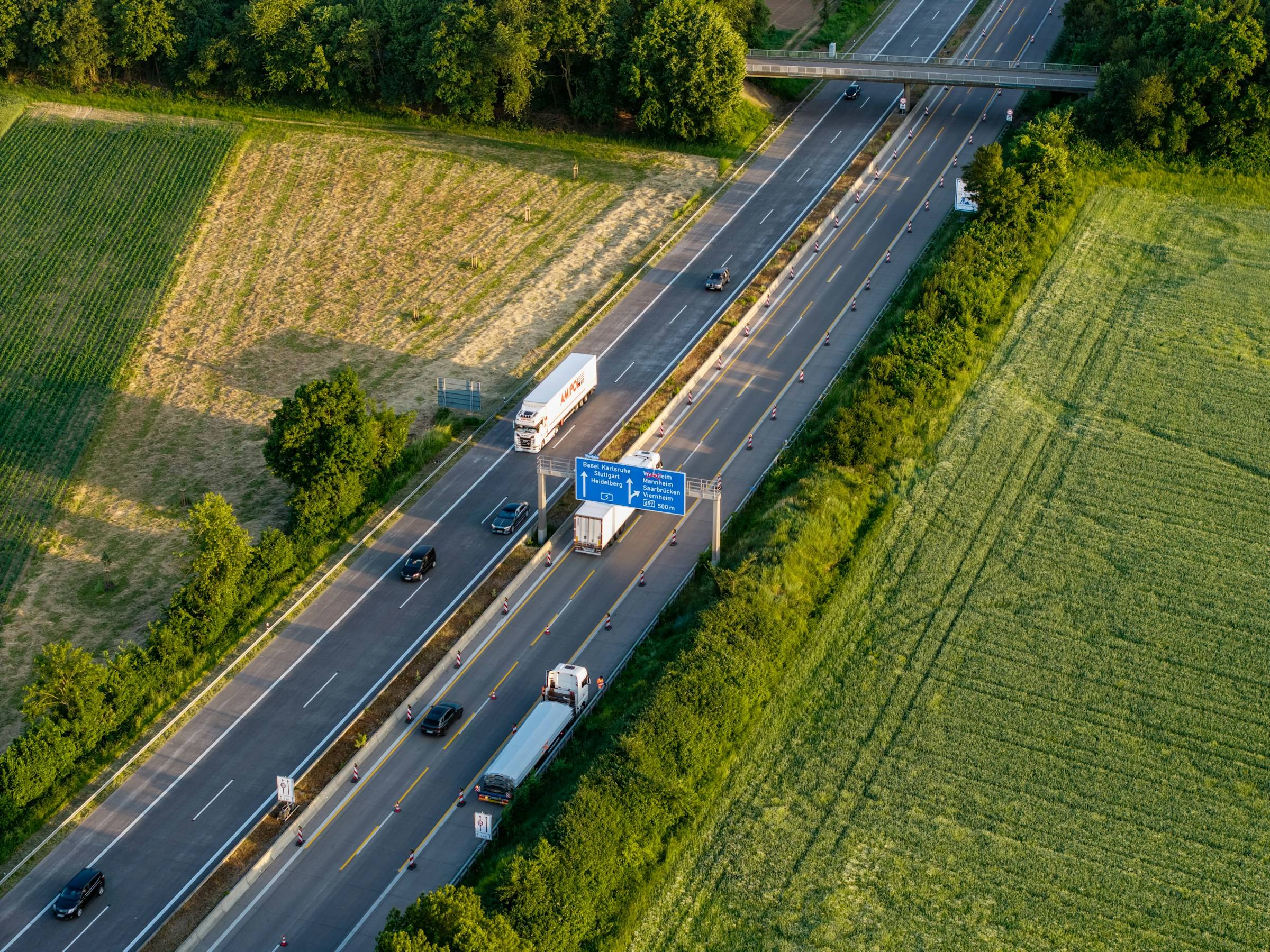 Autostradă cu camioane printre câmpuri, văzută de sus